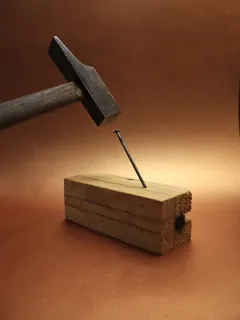 Martillo clavando un clavo en madera en fondo de carpintería
