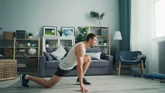 Hombre haciendo flexiones en la sala de estar, ejercicio en casa