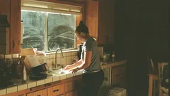 Mujer lavando platos en cocina con cámara Canon A-1 y película Lomo 800