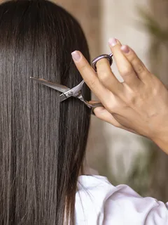 Mujer cortándose el cabello con tijeras en casa