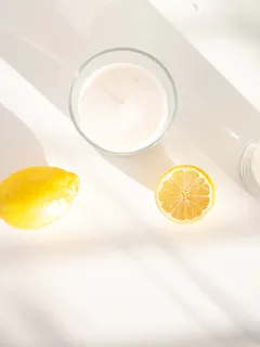 Vaso transparente con líquido blanco junto a fruta limón