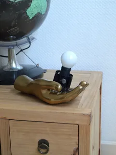 Lámpara hecha con objetos reciclados sobre cómoda de madera con globo terráqueo