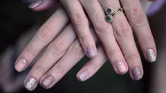 Manicura femenina con esmalte y anillo en los dedos